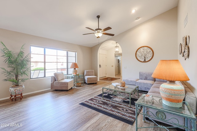 living room with ceiling fan, light wood-type flooring, and vaulted ceiling