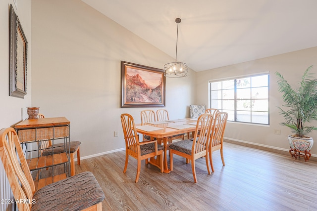 dining room with a chandelier, vaulted ceiling, and light hardwood / wood-style flooring