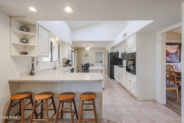 kitchen with a kitchen breakfast bar, white cabinetry, black appliances, and lofted ceiling