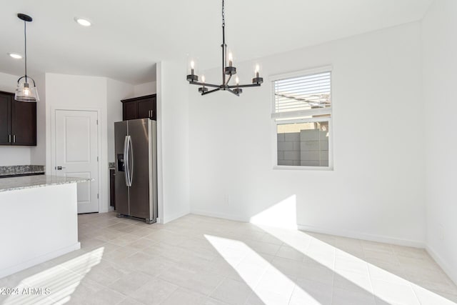 kitchen with a chandelier, stainless steel fridge, dark brown cabinets, and pendant lighting