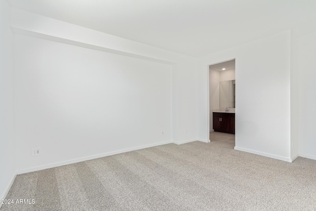 empty room featuring sink and light carpet