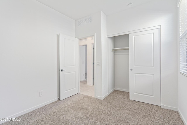 unfurnished bedroom with light carpet and a closet