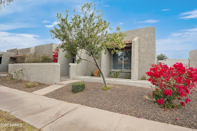 view of front of home with a fenced front yard, a gate, a tile roof, and stucco siding