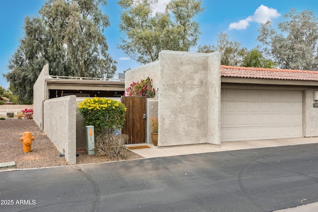 view of front of property featuring a garage, a gate, fence, and stucco siding