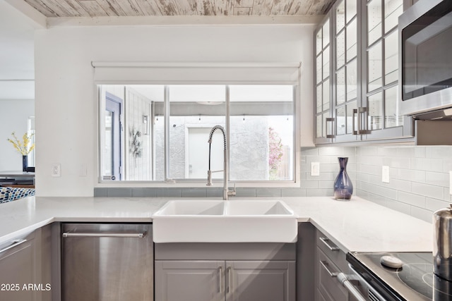 kitchen featuring tasteful backsplash, wood ceiling, appliances with stainless steel finishes, gray cabinetry, and a sink