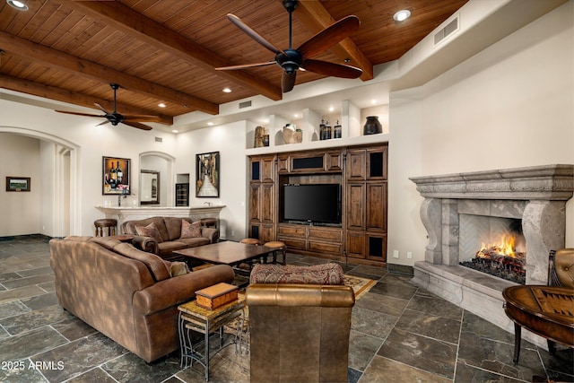 living room featuring ceiling fan, a fireplace, wooden ceiling, and beamed ceiling