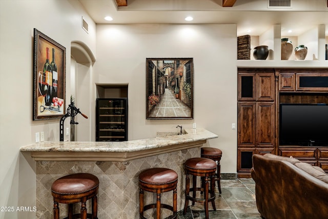 bar featuring light stone countertops and wine cooler