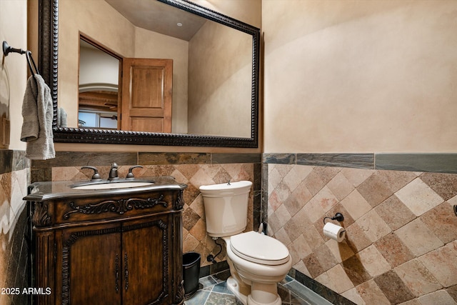 bathroom featuring vanity, toilet, and tile walls