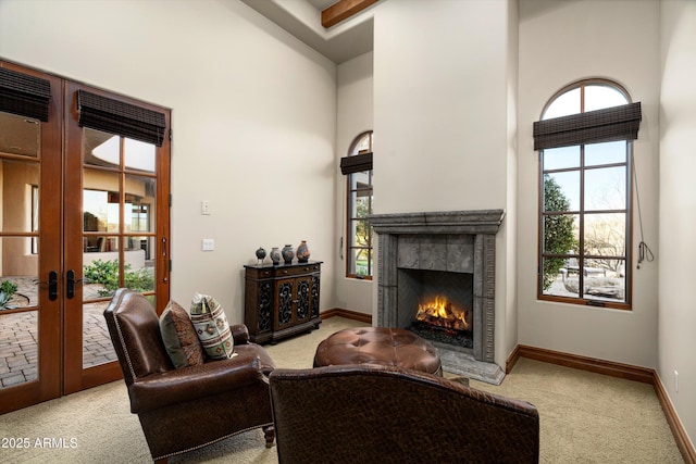 carpeted living room with french doors, a towering ceiling, and a wealth of natural light