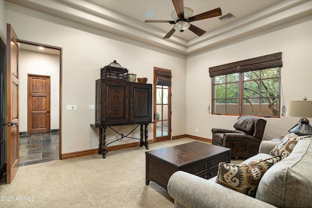 carpeted living room featuring ceiling fan and a tray ceiling