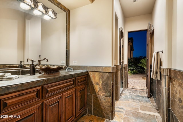 bathroom with vanity and tile walls