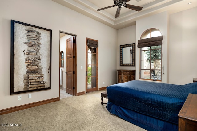 carpeted bedroom with a tray ceiling and ceiling fan