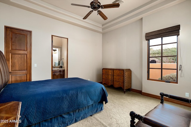 bedroom featuring a raised ceiling, ceiling fan, carpet floors, and ensuite bath