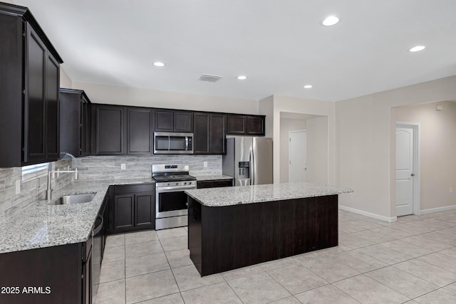 29402 W Mitchell Ave, Buckeye, AZ 85396 - kitchen featuring stainless steel appliances, a kitchen island, a sink, backsplash, and light stone countertops