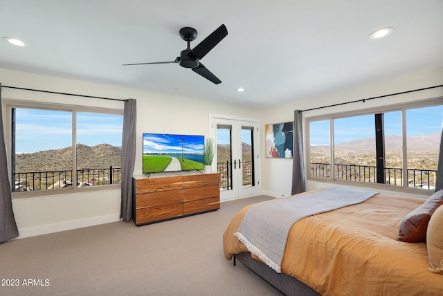 carpeted bedroom with ceiling fan, multiple windows, a mountain view, and french doors