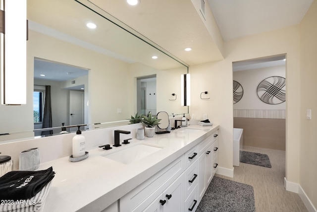 bathroom featuring a bathing tub, double sink, and large vanity