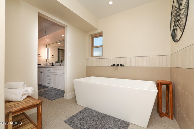 bathroom with tile walls, tile floors, a bathtub, and vanity