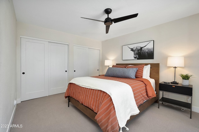 carpeted bedroom with ceiling fan and multiple closets