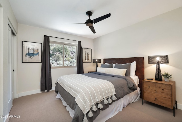 bedroom with ceiling fan, light carpet, and a closet