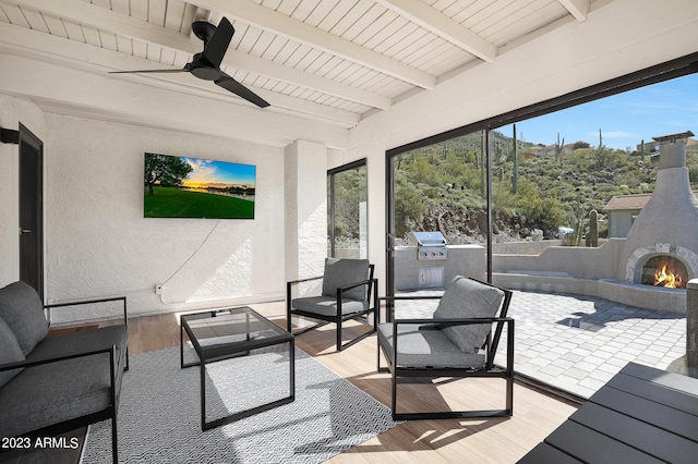 sunroom with exterior fireplace, ceiling fan, and beamed ceiling