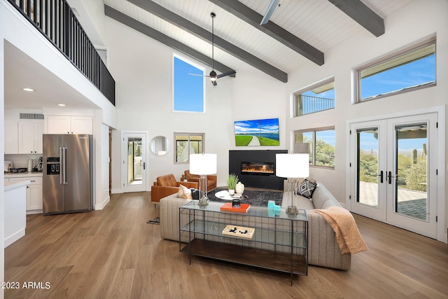 living room with high vaulted ceiling, beam ceiling, ceiling fan, french doors, and light wood-type flooring