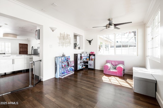 game room with dark wood-style flooring, ornamental molding, baseboards, and ceiling fan