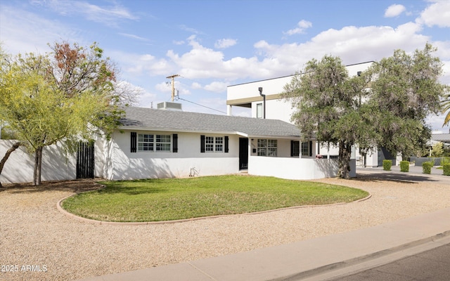 view of front of home featuring a shingled roof, stucco siding, and a front yard