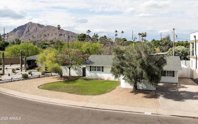 ranch-style home with concrete driveway, stucco siding, fence, and a front lawn