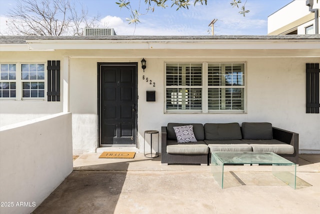 entrance to property with outdoor lounge area, stucco siding, and central AC