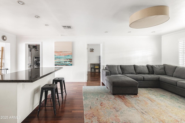 living area featuring crown molding, washer / clothes dryer, visible vents, and dark wood-style floors