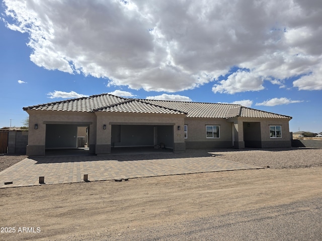 view of front of home featuring a tiled roof, stucco siding, an attached garage, and decorative driveway