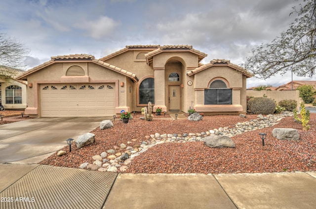 mediterranean / spanish-style house with a garage, driveway, a tiled roof, and stucco siding