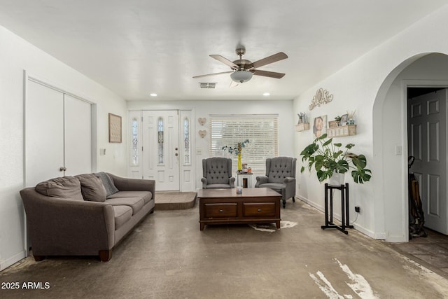 living room featuring baseboards, visible vents, ceiling fan, arched walkways, and concrete flooring