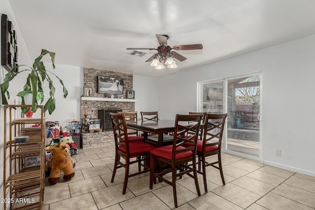 dining room featuring visible vents, a ceiling fan, light tile patterned floors, and a fireplace