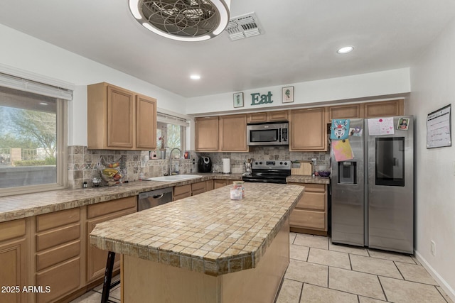 kitchen featuring tasteful backsplash, light countertops, visible vents, stainless steel appliances, and a sink