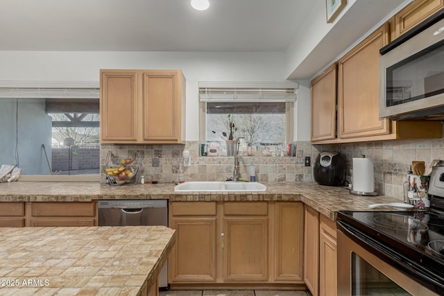 kitchen with light countertops, decorative backsplash, a sink, and stainless steel appliances