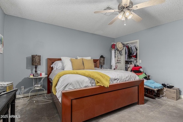 bedroom featuring ceiling fan, a textured ceiling, a closet, a walk in closet, and baseboards