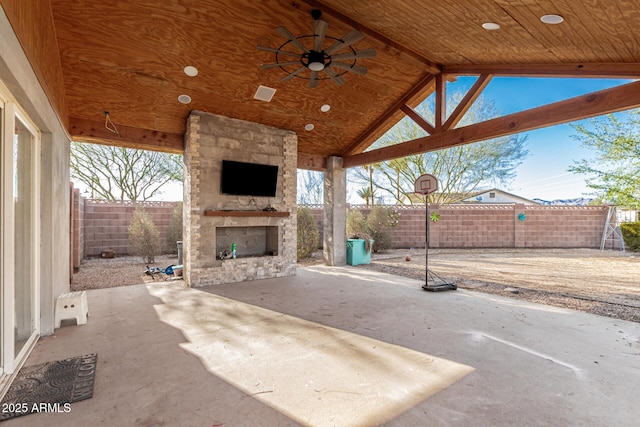 view of patio with a fenced backyard, a ceiling fan, and an outdoor stone fireplace