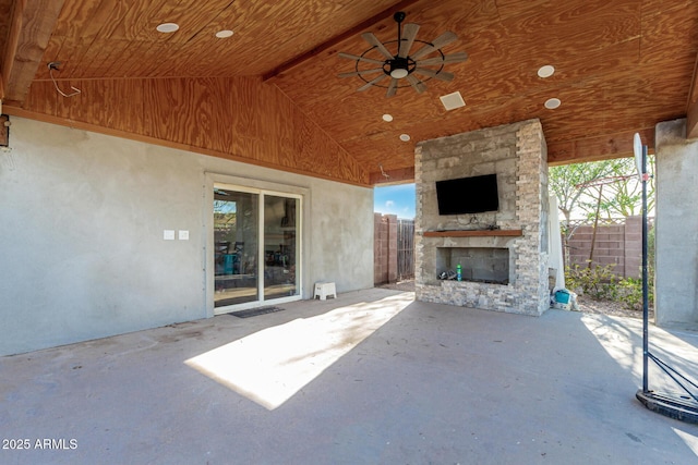 view of patio / terrace featuring an outdoor stone fireplace, fence, and a ceiling fan