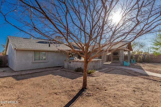 back of house with a patio area, roof with shingles, stucco siding, and fence