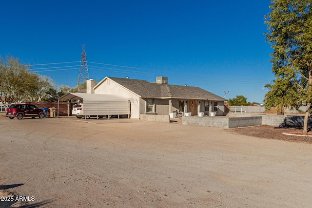 ranch-style home with driveway, cooling unit, a chimney, and stucco siding