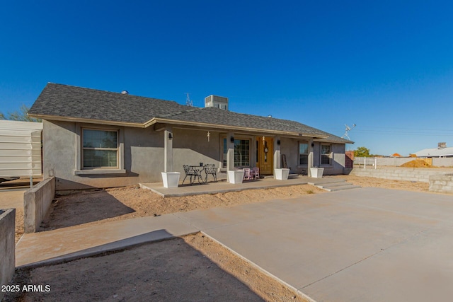 back of property with roof with shingles, a patio area, and stucco siding