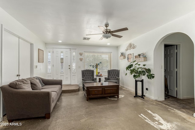 living room featuring concrete floors, baseboards, a ceiling fan, visible vents, and arched walkways