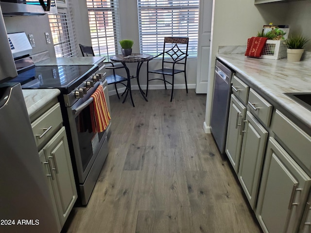 kitchen featuring range, stainless steel dishwasher, gray cabinetry, and light hardwood / wood-style floors