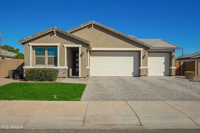 view of front of home featuring decorative driveway, stone siding, fence, and stucco siding