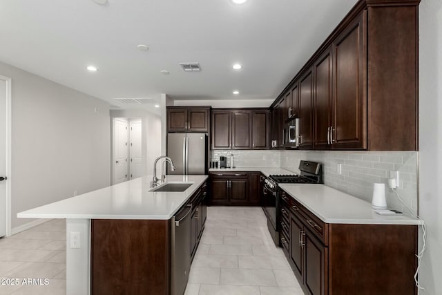 kitchen with dark brown cabinetry, stainless steel appliances, a sink, visible vents, and light countertops