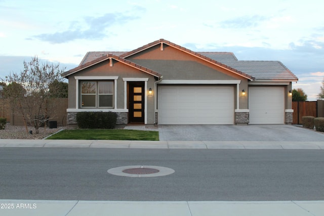 view of front facade with a garage, concrete driveway, stone siding, a tiled roof, and stucco siding