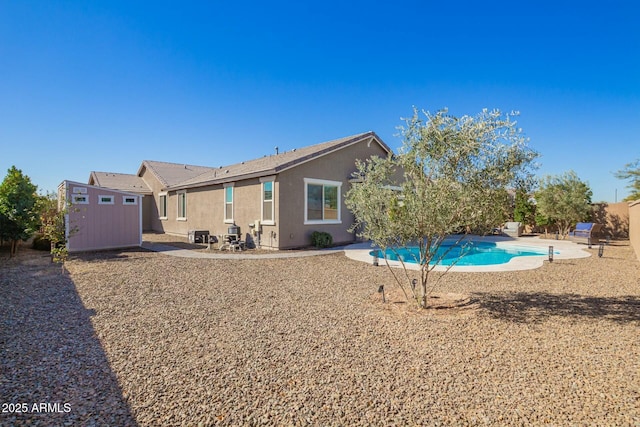 rear view of property featuring stucco siding, a patio area, an outdoor structure, and a shed