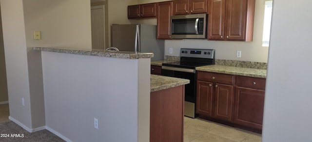 kitchen with light stone countertops, stainless steel appliances, and light tile patterned floors