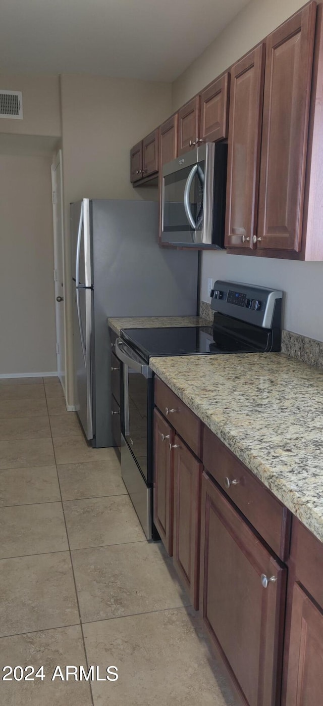 kitchen with light stone countertops, stainless steel appliances, and light tile patterned floors